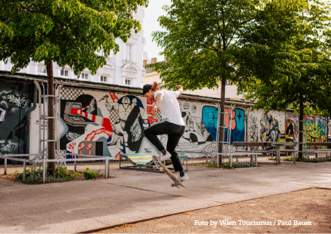 Skateboarder in einem Wiener Stadtpark vor Graffiti.